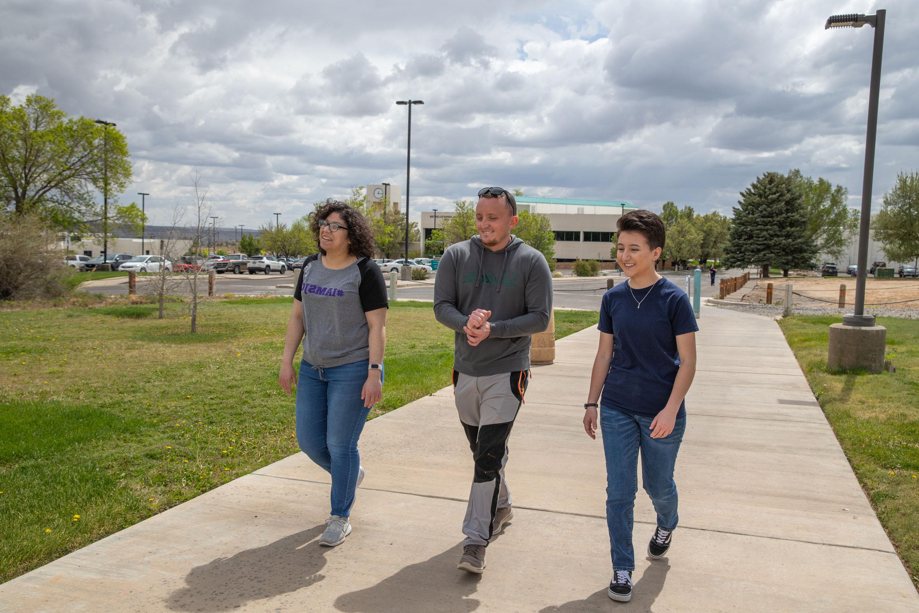 Three students smiling walking across the SJC Campus